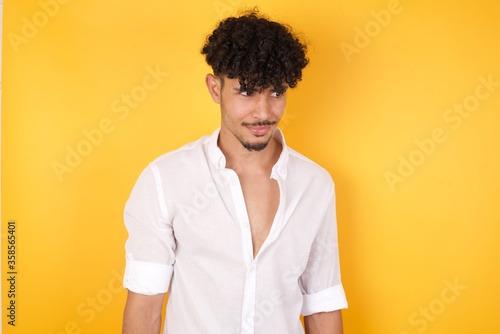 Photo of amazed puzzled young Caucasian male, curves lips and has worried look, sees something awful in front, isolated on white background, dressed in jean overalls.