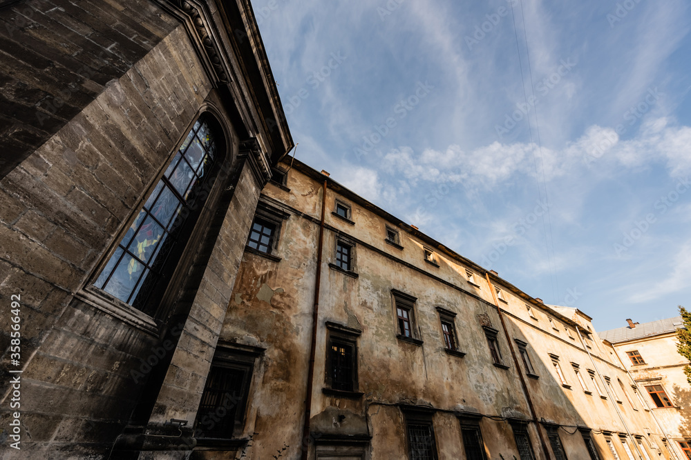 low angle view of old stone building against blue sky in lviv, ukraine