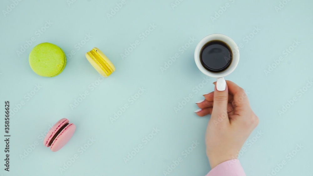 Macaroons or macaron on pastel blue surface with espresso in white cup. Macaroons or macaron on pastel blue surface with espresso in white cup.