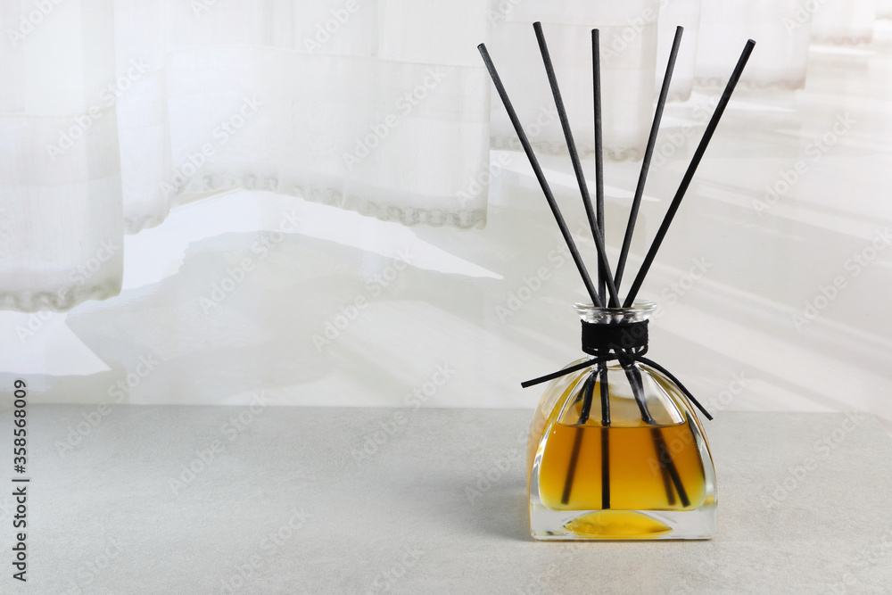 luxury aromatic scented reed diffuser glass bottle display on the grey table in the white bedroom near the curtain of the hotel resort luxury aromatic scented reed diffuser glass bottle display on the grey table in the white bedroom near the curtain of the hotel resort