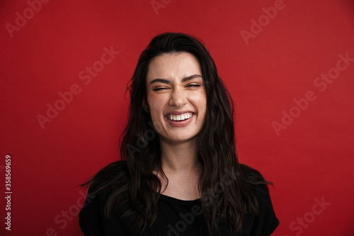Photo of brunette cheerful woman in casual t-shirt laughing at camera