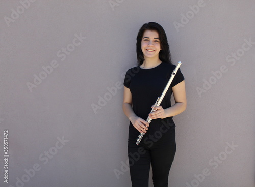 Photo Black-haired girl holds the flute outside in front of a grey background