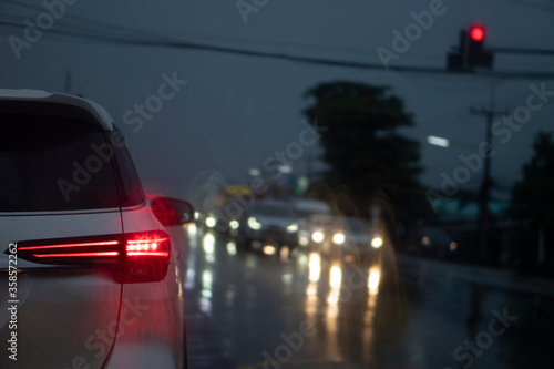 Abstract of cars parked at a traffic signal at an intersection. The road condition is wet with rain. And during the night time.
