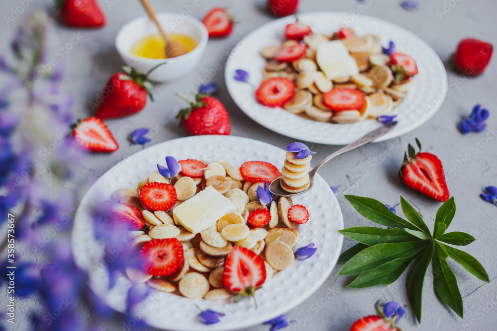 Pancake cereal, trendy food. Mini cereal pancakes with butter, honey, and strawberries. Pancake cereal, trendy food. Mini cereal pancakes with butter, honey, and strawberries.