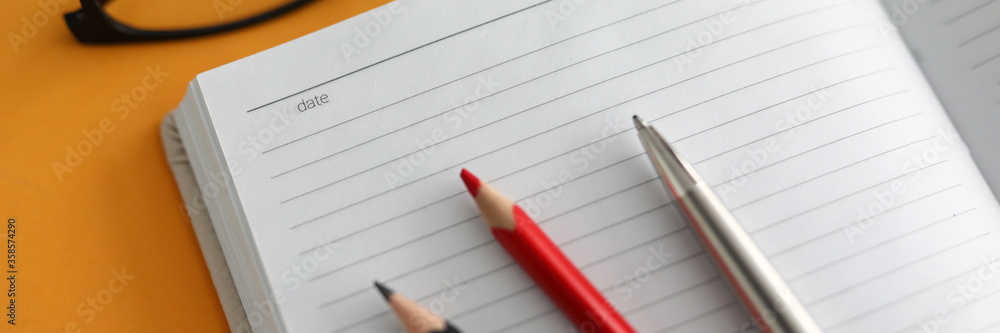 Close-up, on open diary lie color pencils and pen Close-up, on open diary lie color pencils and pen
