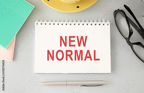 New normal concept effected by COVID 19 coronavirus that changes our lifestyle to new normal presented in word written in notebook on office desk when abnormal becomes new normal .