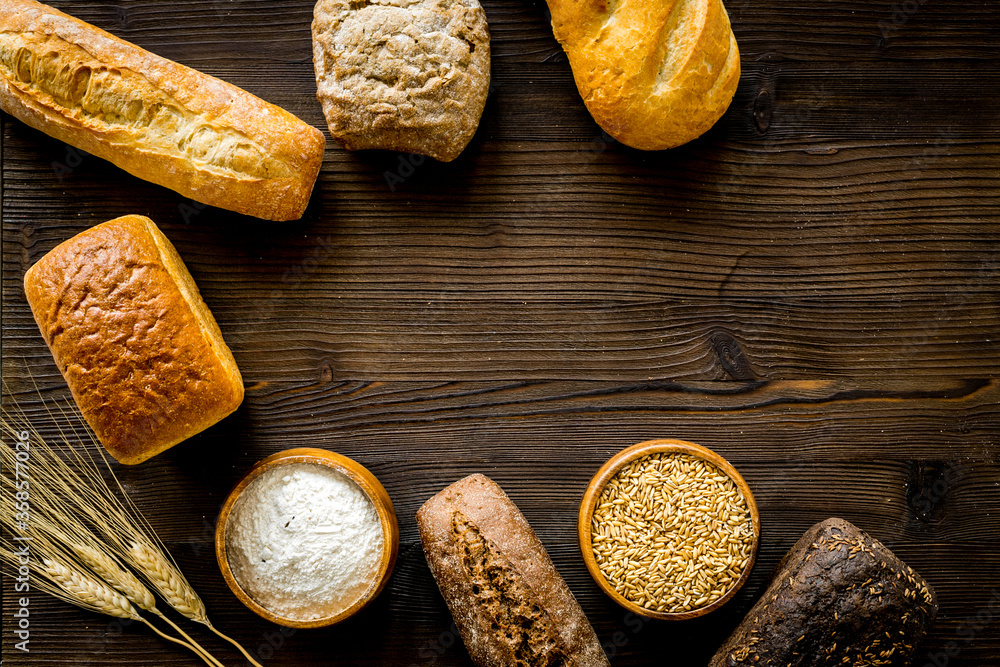Wholegrain bread near wheat ears on wooden desk from above space for text Wholegrain bread near wheat ears on wooden desk from above space for text