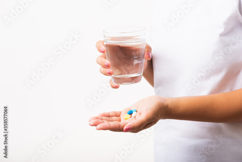 Closeup young Asian woman hold pill drugs in hand ready take medicines with a glass of water, studio shot isolated on white background, Healthcare and medical pharmacy concept