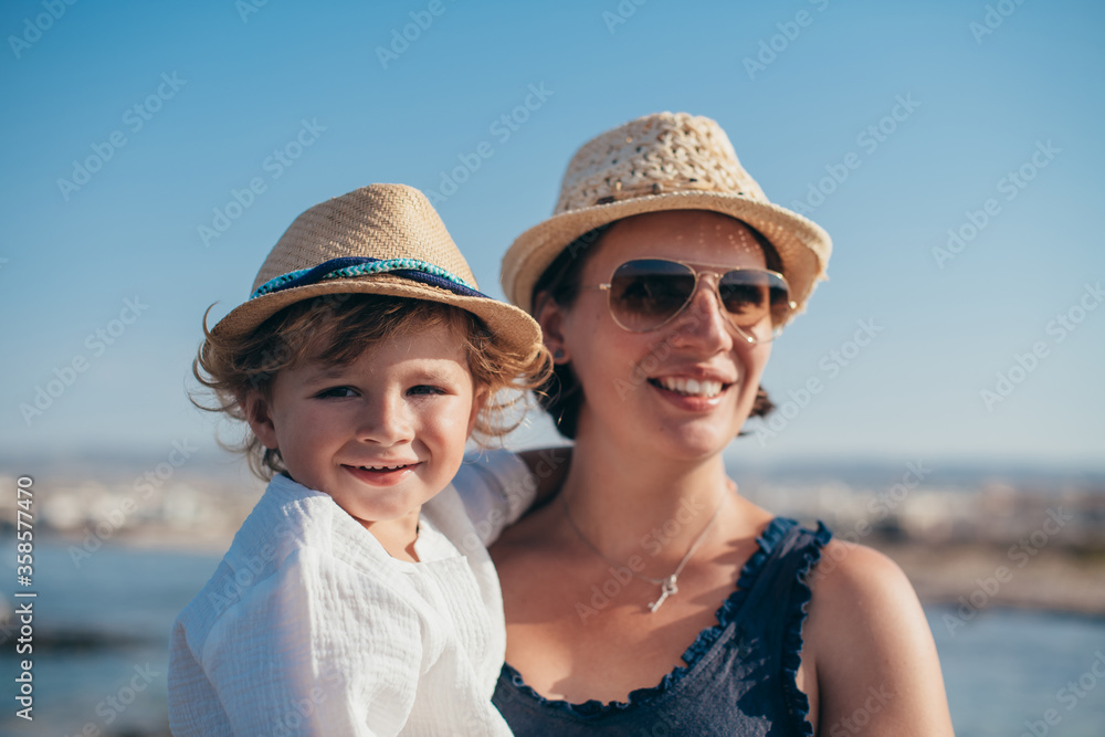Portrait of a happy mom with a little son on a trip near the sea.