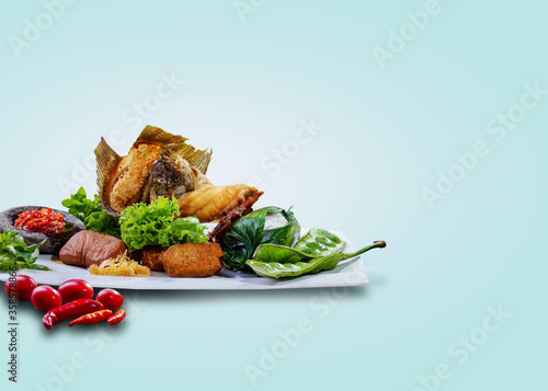 Lead rice with side dishes in the form of crispy fried fish, chili anchovy, fried tofu and tempeh, lettuce, and petai or pete. photo