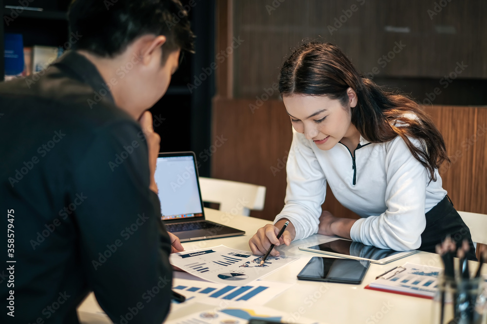Fototapeta premium Two young asian modern people planning work together as a team and present ideas at work. Creative business team sitting working together at office.