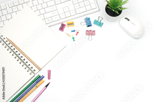 Flat lay business office concept on modern white table desk background with blank notebook on white keyboard computer, mouse and eyeglasses, green plant and coffee cup,Top view with copy space