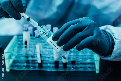 A biologist with gloves, mask, and glasses loads a syringe with a dose of Dexamethasone (covid-19 coronavirus cure) photo