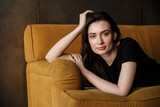 Photo of beautiful young brunette woman lying on couch in apartment