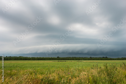 Approaching thunderstorm with arcus (shelf cloud) over plain landscape photo