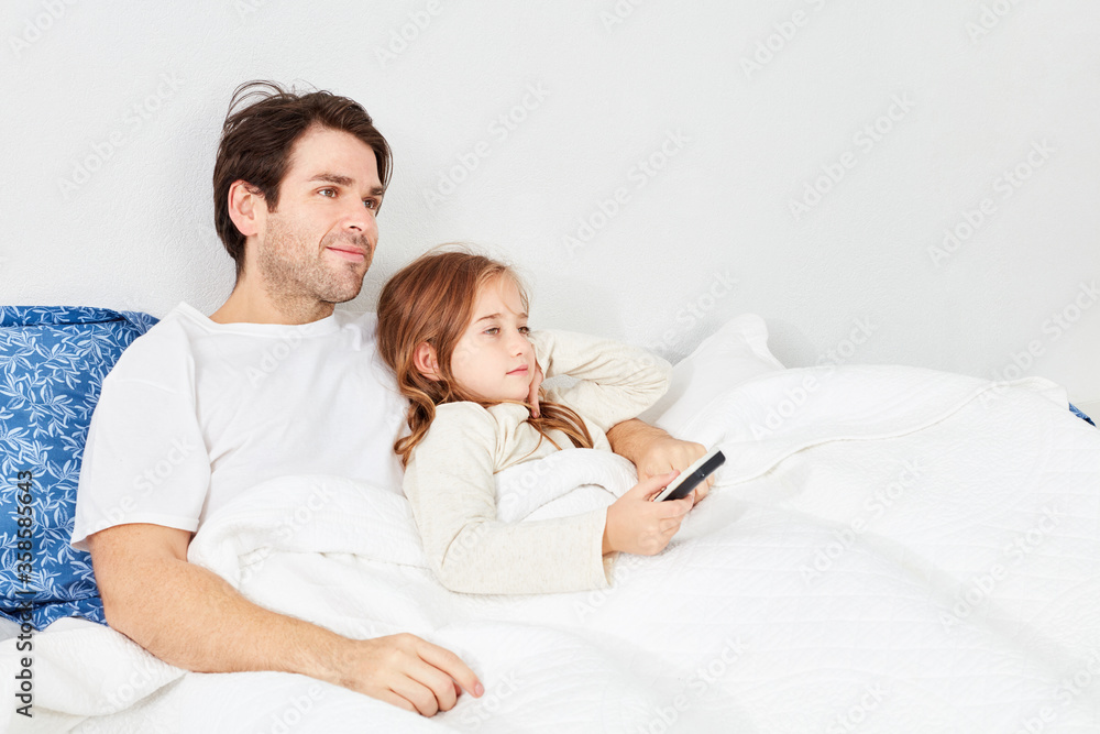 Father and daughter in bed with remote control Father and daughter in bed with remote control