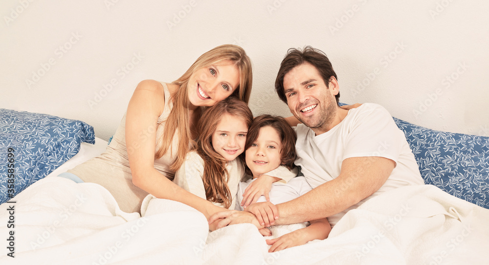 Happy family with two kids in bed