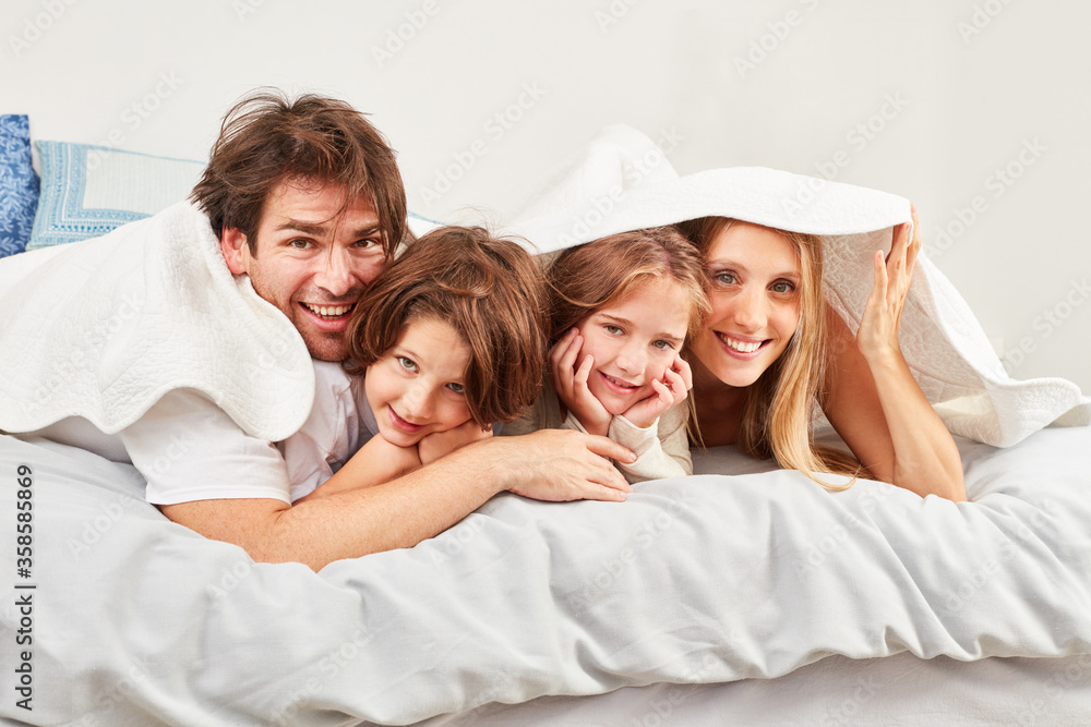 Family with two children under a coverlet