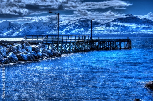 majestic pier in dreamy blue fjord with snowy mountain in background