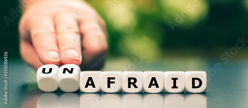 Fotografie Hand turns dice and changes the word afraid to unafraid.