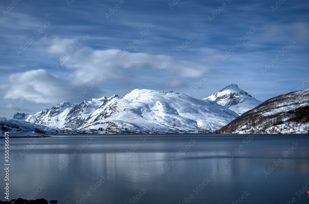 snowy mountain range with deep blue fjord and vivid sky in northern Norway