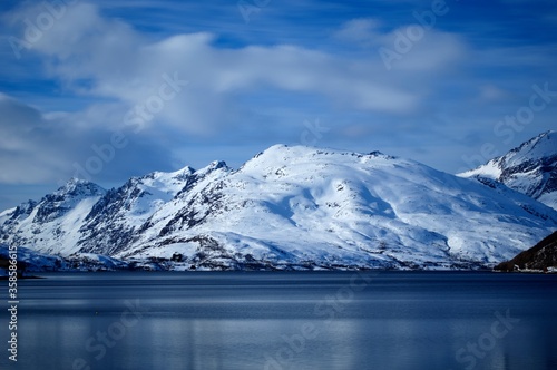 snowy mountain range with deep blue fjord and vivid sky in northern Norway