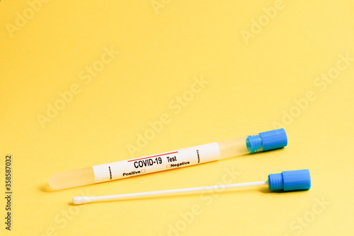 Cotton stick for buccal swab and test tube for COVID 19 diagnostics on yellow background