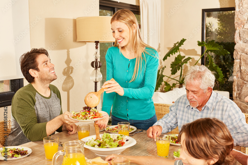 Woman is filling dishes from man with healthy salad