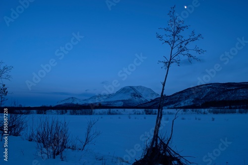 mountain and frozen river landscape lit by moon