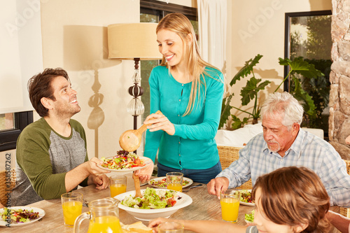 Woman is filling dishes from man with healthy salad