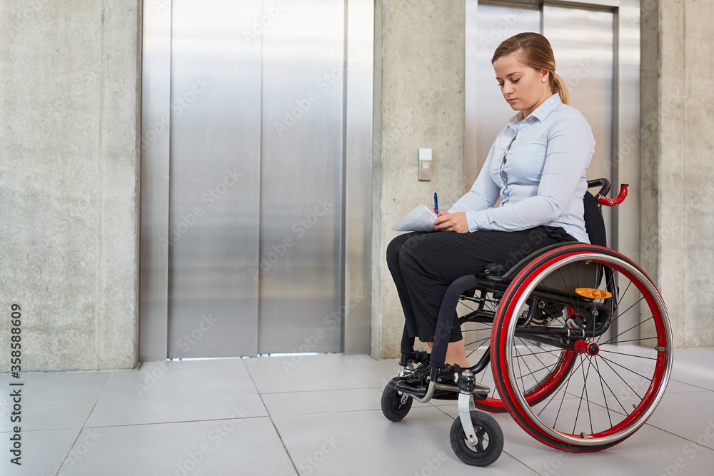 Young woman in a wheelchair in front of an elevator Young woman in a wheelchair in front of an elevator