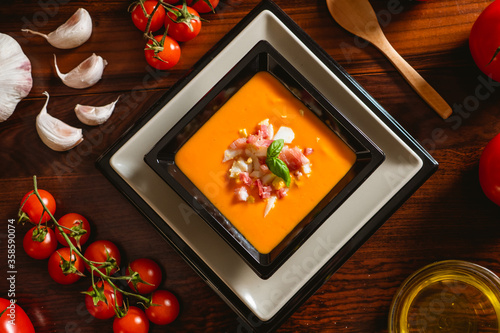 Receta típica española de salmorejo cordobés en un plato cuadrado y con algunos ingredientes al rededor. photo