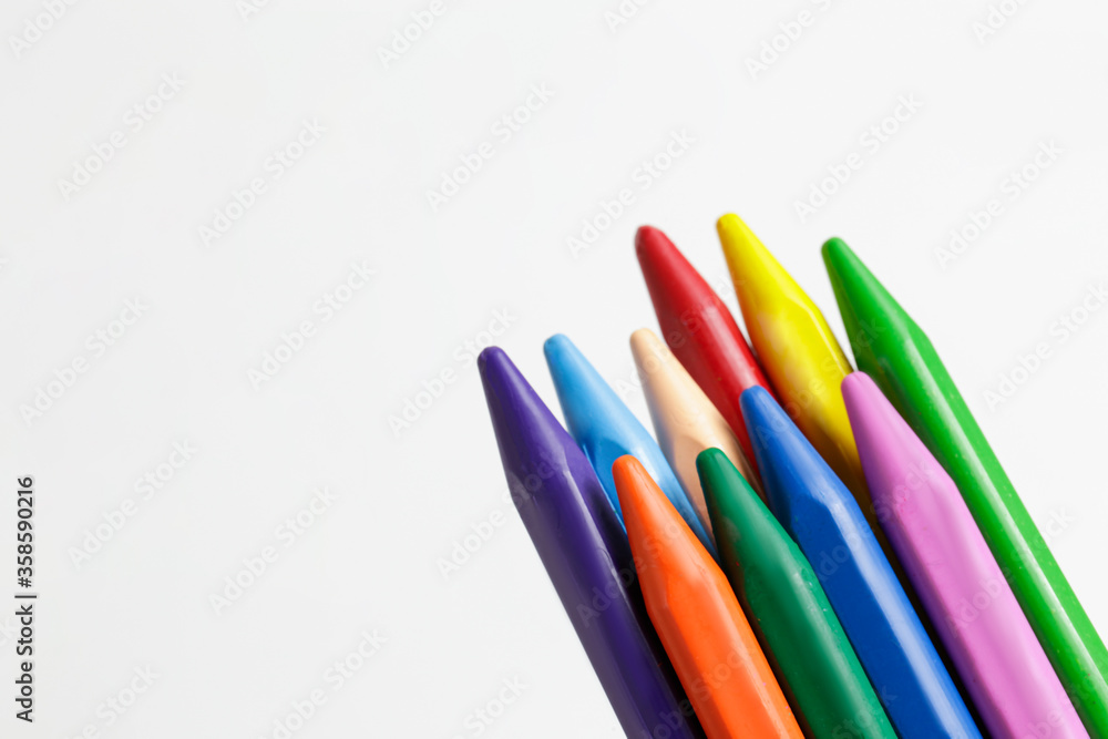 Bunch of different colorful wax crayon pencils laid oun in composition, isolated on white. Soft pastel for drawing in stack. Close up, copy space, top view.