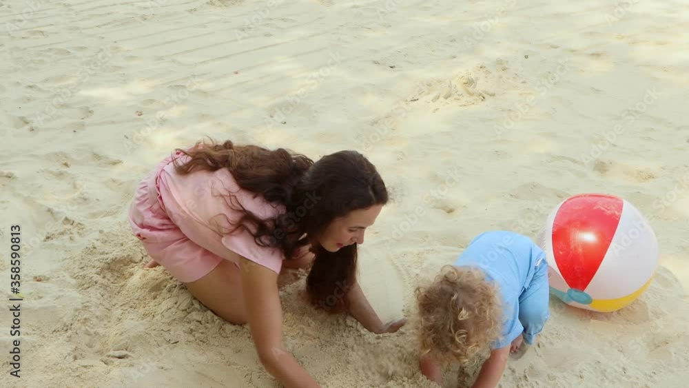 Mom and son 2 years old play on the beach on a Sunny summer day.4K Mom and son 2 years old play on the beach on a Sunny summer day.4K