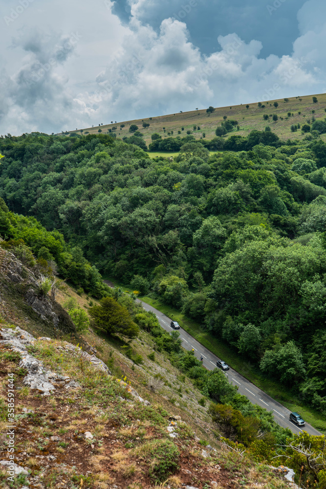 View down onto Cliff Road at the Cheddar Gorge near Bristol in North Somerset.  One car can just be seen driving along the bendy winding A road.  Trees, cliffs and nature frame the image