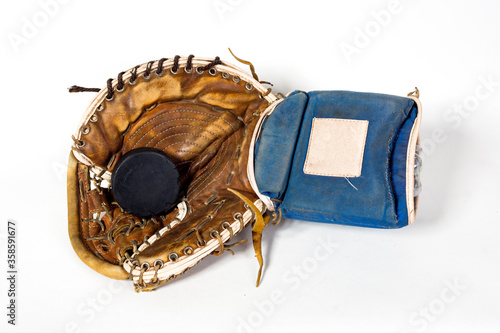 An old hockey glove of a goalkeeper with a hockey puck on a white background.