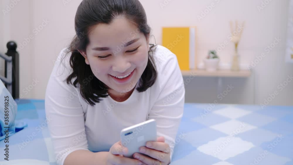 Asian woman looking and touching smartphone relax enjoy and smile with online social media in bedroom. Asian woman looking and touching smartphone relax enjoy and smile with online social media in bedroom.
