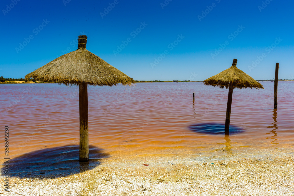 It's Wooden umbrella on the coast of the pink water lake, Senegal, Africa It's Wooden umbrella on the coast of the pink water lake, Senegal, Africa