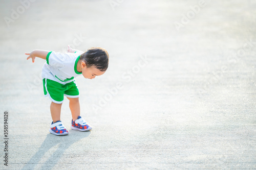 Fotografía Infant child baby boy standing upside down and looking down on the concrete background with free text copy space