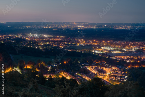 Dusk or night time landscape over small british town Malvern, showing street lamps, and denser populations in the distance. © Rhys