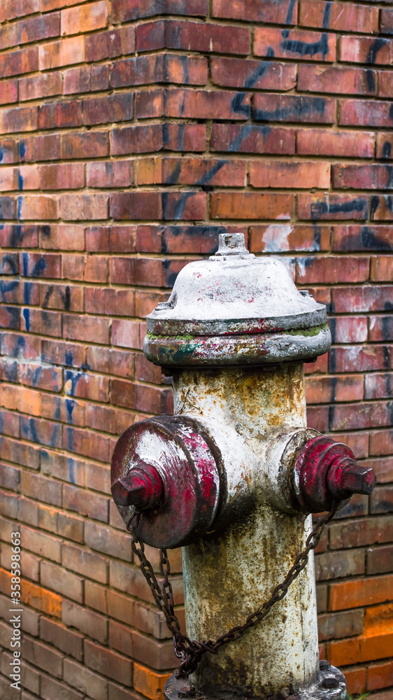Fototapeta premium Old Rusty vintage fire hydrant, brick wall in the background 