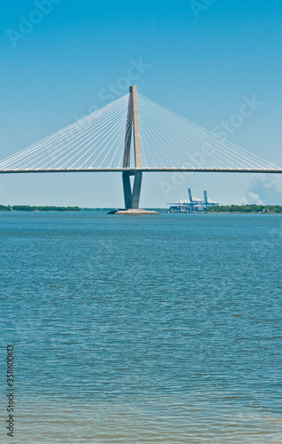 Front view, very far distance of a cable spaced bridge crossing a large, body of water, on a sunny afternoon 