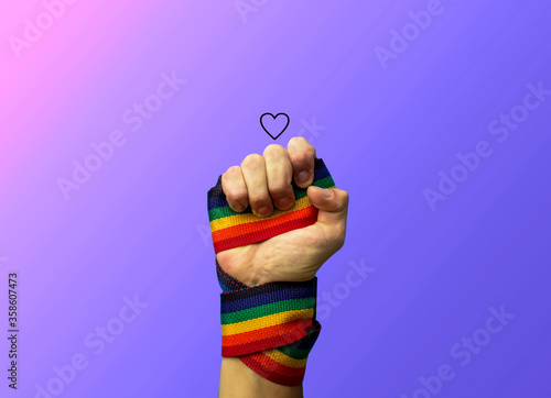 Hand punching up with lgbt flag, purple background 