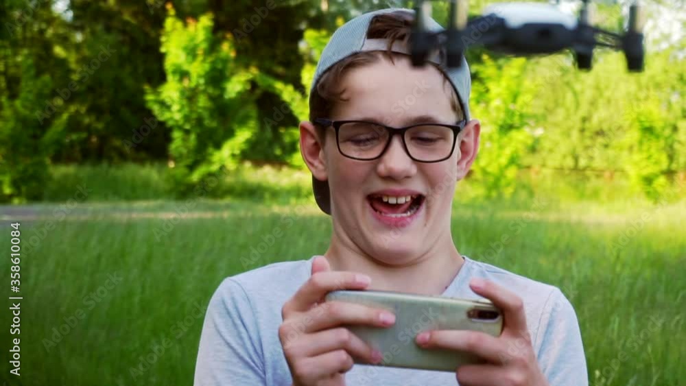 boy who controls a drone from his smartphone on a sunny summer day boy who controls a drone from his smartphone on a sunny summer day