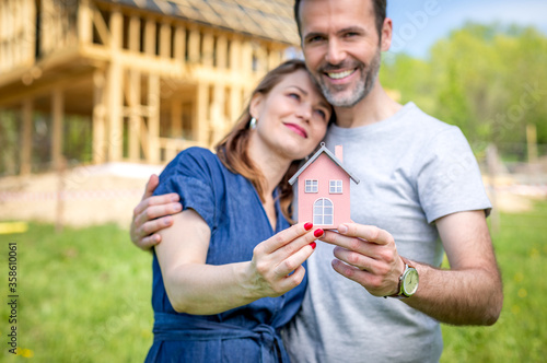 Loving couple building their own home with house under construction in background photo