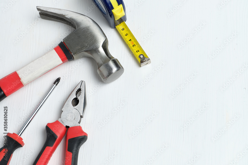 Repairman intruments hammer, screwdriver, measuring tape on white wooden background with copy space and top view. Repairman intruments hammer, screwdriver, measuring tape on white wooden background with copy space and top view.