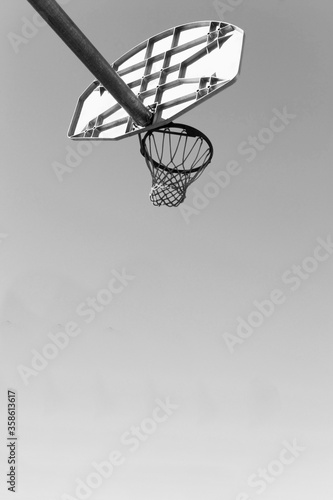 Low angled black and white photograph of a basket ball net and hoop and backboard © moodboard