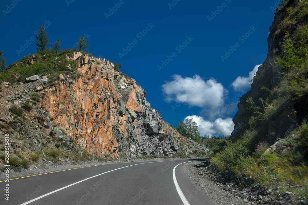Fototapeta premium asphalt road, highway in the mountains. Blue sky and big white clouds. summer landscape
