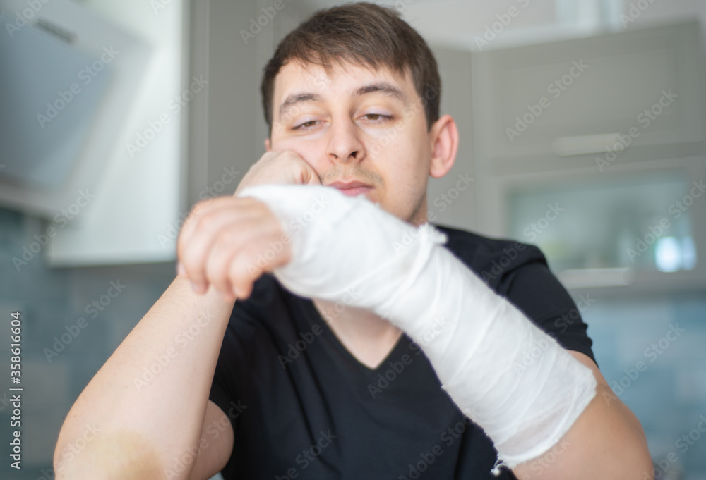 Fracture arm. Health restrictions. Sad man with a broken hand Fracture arm. Health restrictions. Sad man with a broken hand