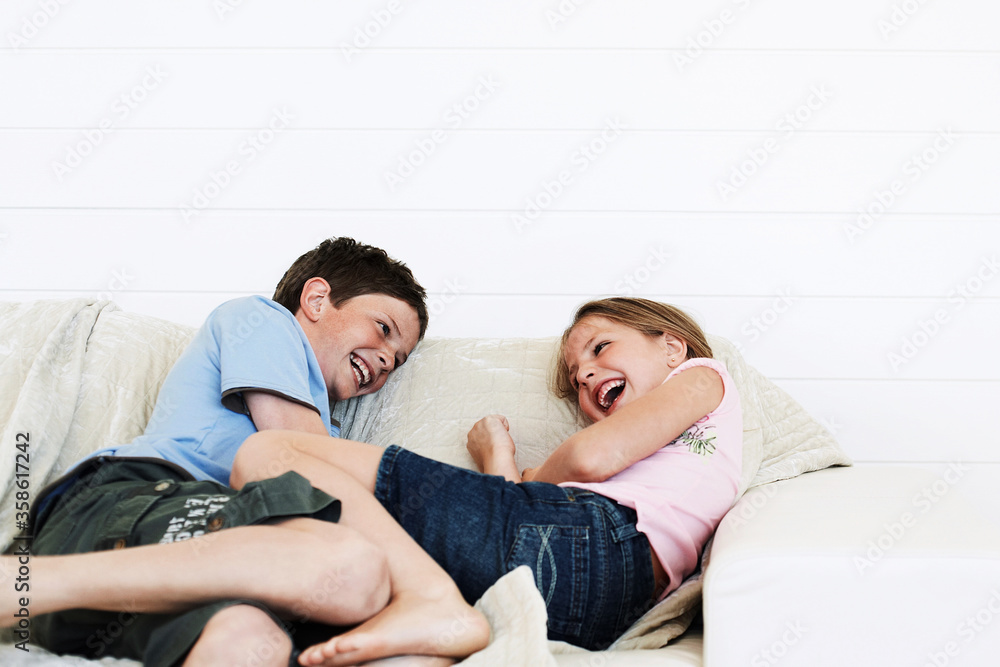 Brother and sister relaxing on sofa together Brother and sister relaxing on sofa together